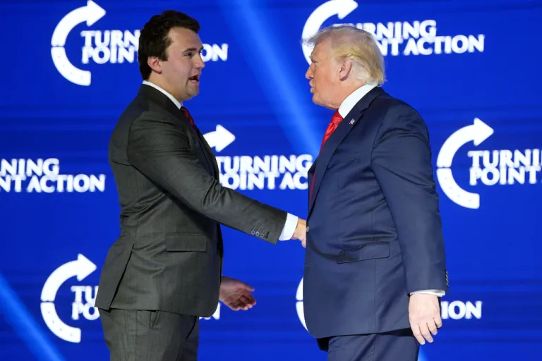 Former President Donald Trump, right, shakes hands with Turning Point CEO Charlie Kirk before speaking during the Turning Point USA Student Action Summit, July 23, 2022, in Tampa, Fla.