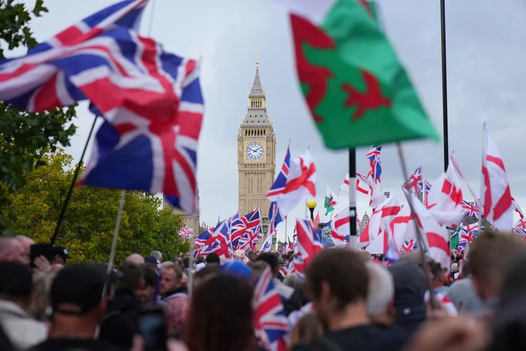 A crowd of people hold British flags with Big Ben in the background.