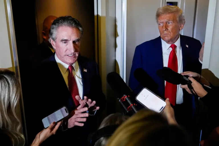 President Donald Trump watches as Interior Secretary Doug Burgum speaks to reporters.