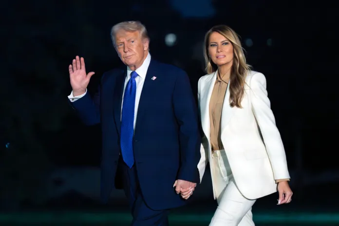 President Donald Trump waves to media while holding hands with first lady Melania Trump as they walk on the South Lawn upon their arrival to the White House, in Washington, Tuesday, Sept. 23, 2025. 