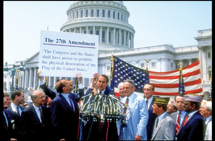 A group of veterans and senators, including Sen. Robert Dole (R-KS), center, pose with the text of a proposed amendment to the U.S. constitution meant to allow bans on the burning of the American flag, June 14, 1990. (Cynthia Johnson/Getty Images)
