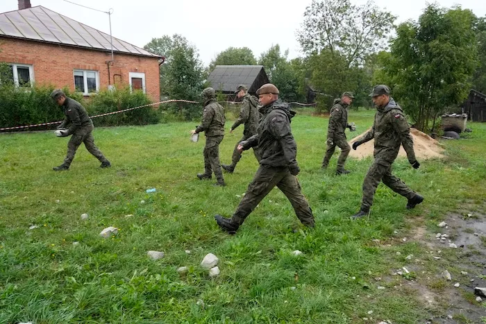 Territorial defense officers pick up debris from the destroyed roof of a house, after Russian drones violated Polish airspace during an attack on Ukraine, in Wyryki near Lublin, Poland, Thursday, Sept. 11, 2025. (AP Photo/Czarek Sokolowski)