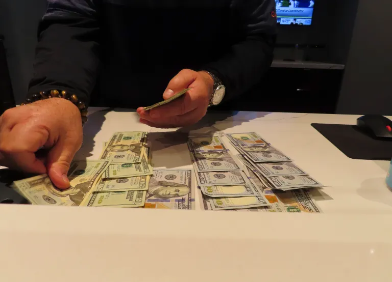 A worker at the sports book in the Ocean Casino Resort counts money on a counter.