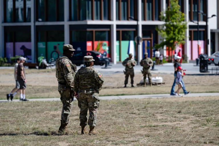 Members of the DC National Guard speak while people walk to Nationals Park, Saturday, Aug. 30, 2025, in Washington. (AP Photo/Jon Cherry)