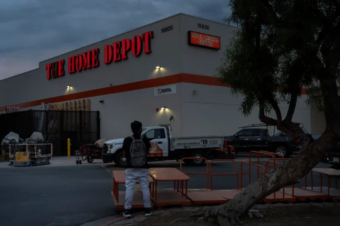 A day laborer waits for work in the parking lot of a Home Depot.