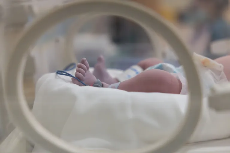 A baby's feet are visible in a hospital incubator.