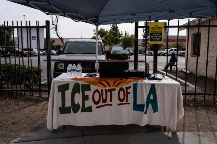 A table covered with a cloth reading "ICE Out of LA" sits under a canopy next to the job center for day laborers outside a Home Depot.