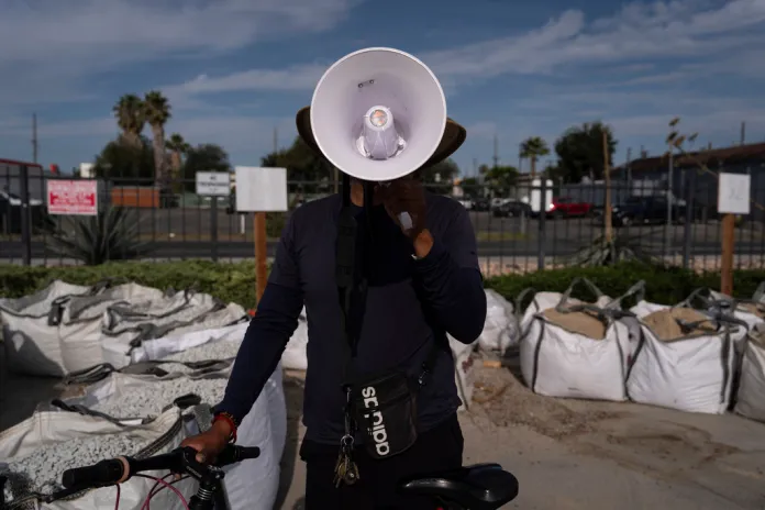 Luis poses with a megaphone in the parking lot of a Home Depot.