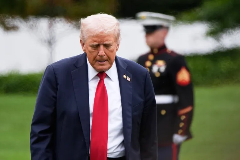 Trump walks with his head down. A Marine can be seen behind him.