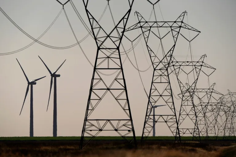Wind turbines rise in the distance behind electric transmission lines at the Spearville Wind Farm, Sunday, Sept. 29, 2024, near Spearville, Kan.