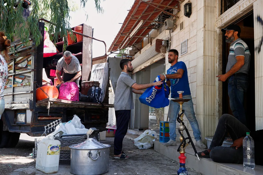 Alawite Syrian men load their belongings onto a truck.