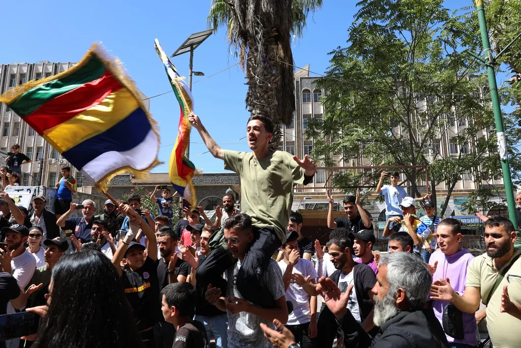People chant slogans while waving the Druze flag.