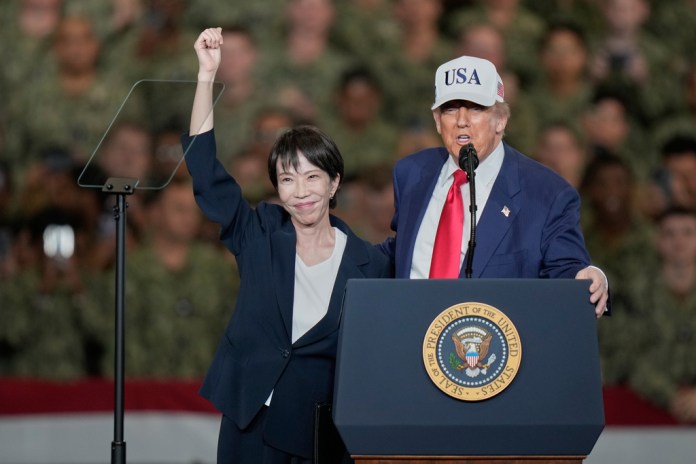 Japanese Prime Minister Sanae Takaichi, left, gestures as U.S. President Donald Trump delivers his speech during their visit to the aircraft carrier USS George Washington at the U.S. Navy's Yokosuka base, in Yokosuka, south of Tokyo, Tuesday, Oct. 28, 2025.