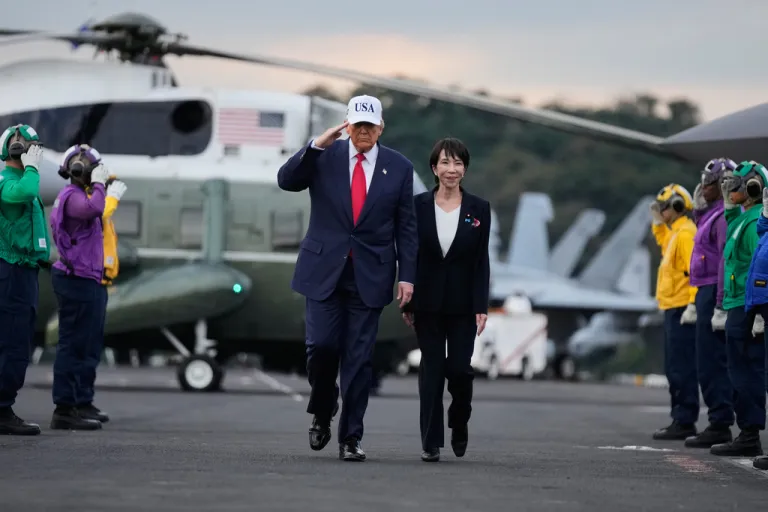 Donald Trump walks on a tarmac with Japanese Prime Minister Sanae Takaichi