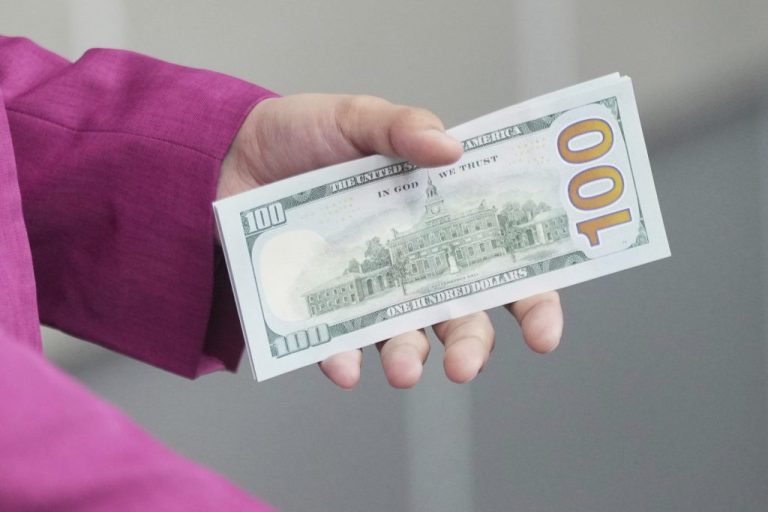 An employee holds U.S. dollar banknotes at a money changer.