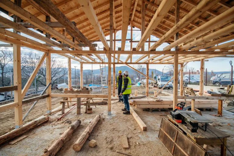Construction workers in building site of wooden house.