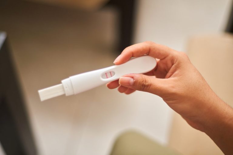 A woman looking at a positive pregnancy test.