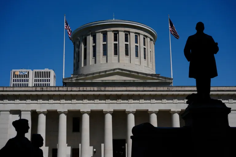 The William McKinley Monument is silhouetted in front of the west side of the Ohio Statehouse.