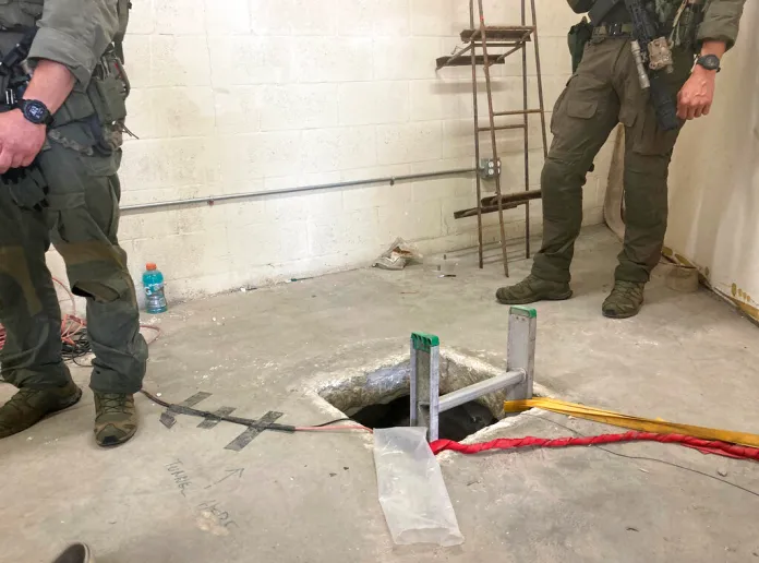 Law enforcement officers stand by the opening of a cross-border tunnel.