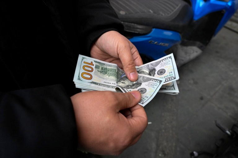 A street money exchanger poses for a photo without showing his face as he counts U.S. dollars.
