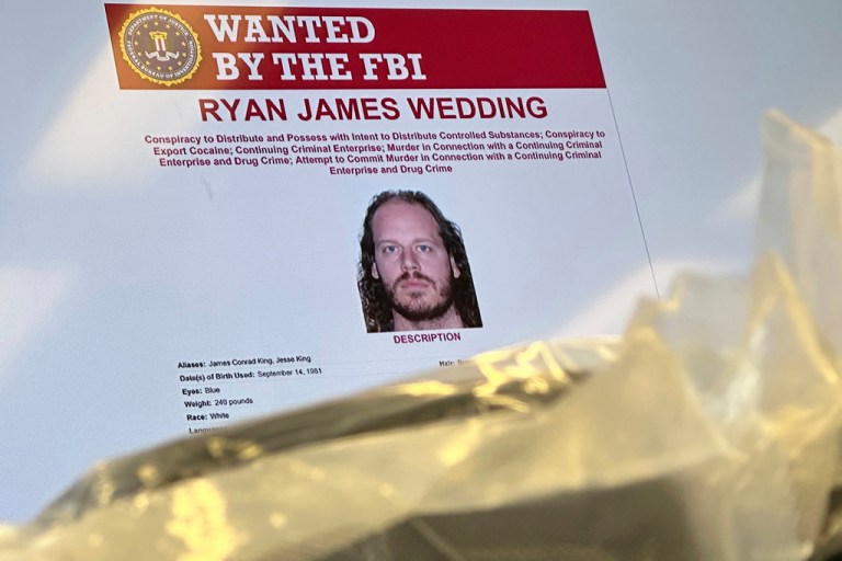 An image of former Canadian Olympic snowboarder Ryan Wedding, who is a fugitive charged with allegedly running and participating in a transnational drug trafficking operation, is displayed on a video monitor along with bricks of cocaine.