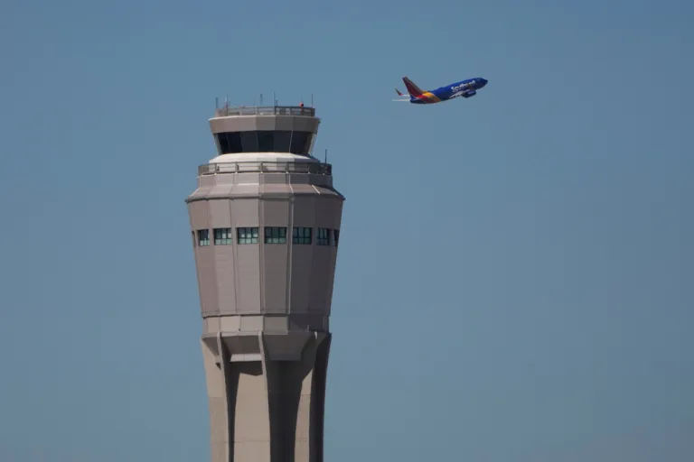 A plane takes off near the air traffic control tower at Harry Reid International Airport, Tuesday, Oct. 7, 2025, in Las Vegas. (AP Photo/John Locher)
