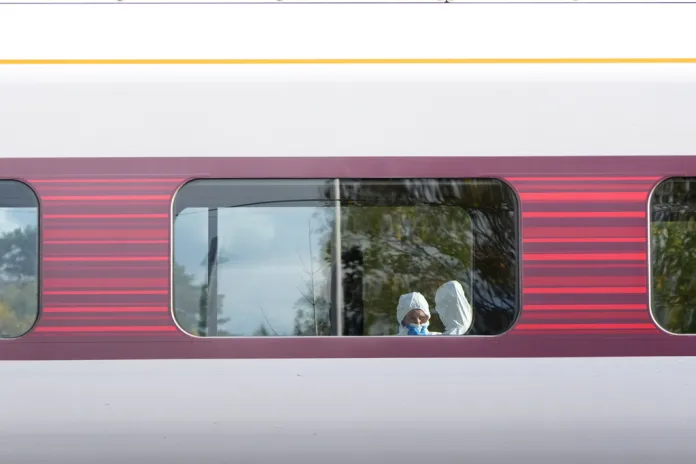 Forensic investigators through the window of a train.