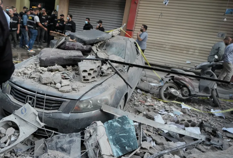 Security officers gather near destroyed vehicles at the site where an Israeli strike hit at an apartment building in Dahiyeh, a southern suburb of Beirut, Sunday, Nov. 23, 2025.