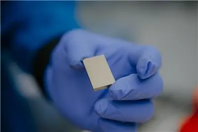 A gloved hand holds a rare earth magnet.