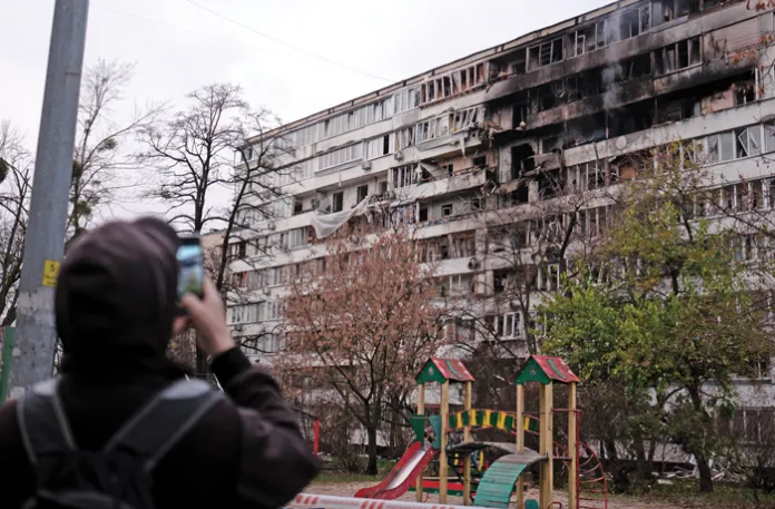 A man takes photos of a damaged apartment building after a Russian drone and missile attack in Kyiv, Nov. 25, 2025. (Vitalii Nosach/Global Images Ukraine/Getty)