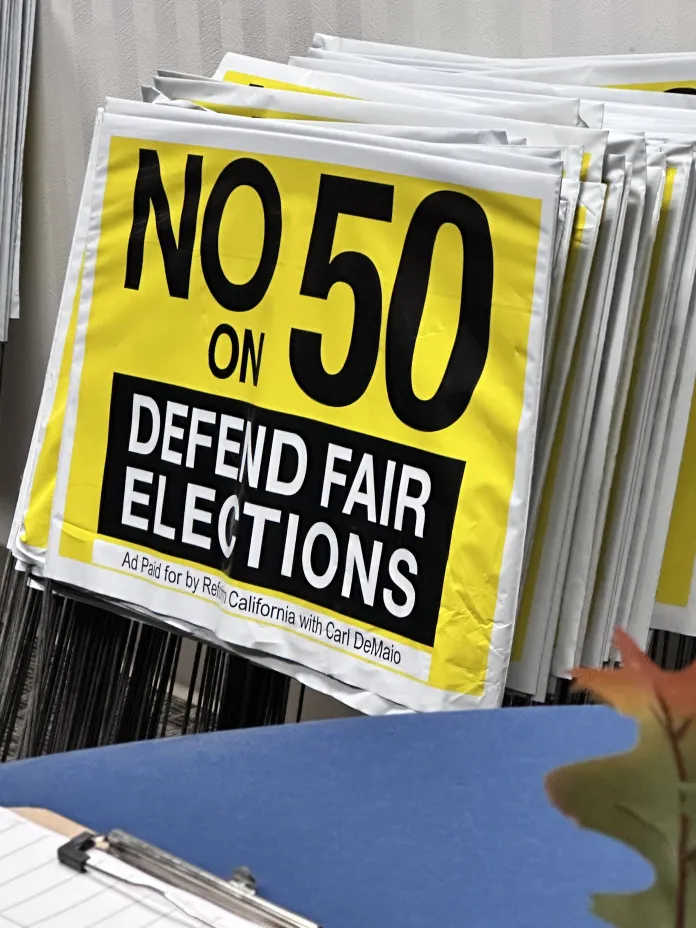 A stack of "No on 50" signs piles up at an event