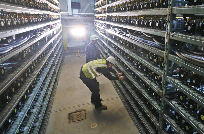 Workers look over racks of Bitcoin data miners during construction of a Bitcoin data center in Virginia Beach, Virginia in 2018. (Steve Helber/AP)