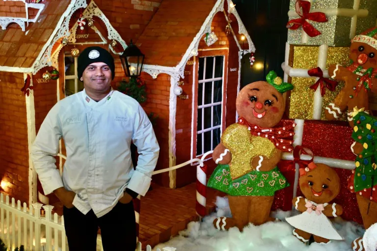Naik poses in front of his gingerbread house creation.