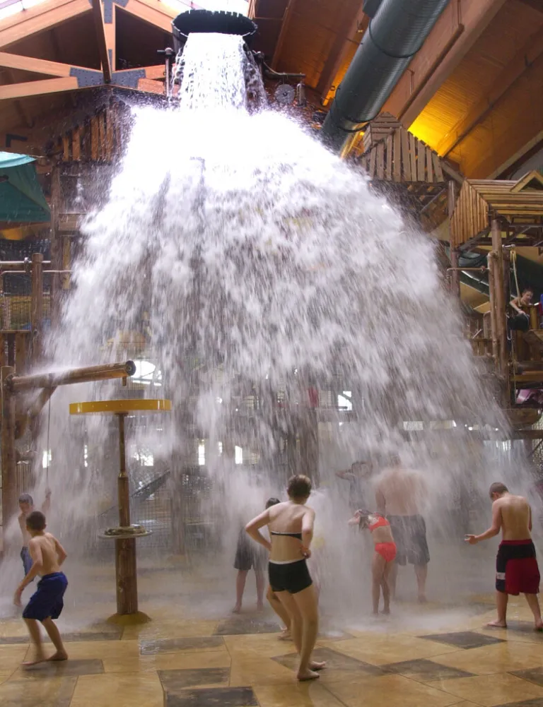 Guests at a Great Wolf Lodge location stand under a bucket as it dumps 1,000 gallons of water June 16, 2003. (AP Photo/Orlin Wagner)
