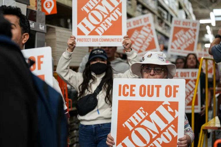 Protesters hold signs as they march through a Home Depot.