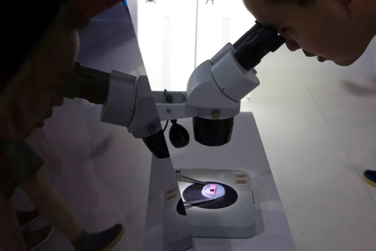 A visitor to the 21st China Beijing International High-tech Expo looks at a computer chip through the microscope displayed by the state-controlled Tsinghua Unigroup project which has emerged as a national champion for Beijing's semiconductor ambitions in Beijing, China, Thursday, May 17, 2018. The Trump administration has threatened to impose tariffs on up to $150 billion in Chinese imports to punish Beijing over trade practices requiring American companies to hand over technology in exchange for access to the Chinese market. China has counterpunched by targeting $50 billion in U.S. products.(AP Photo/Ng Han Guan)