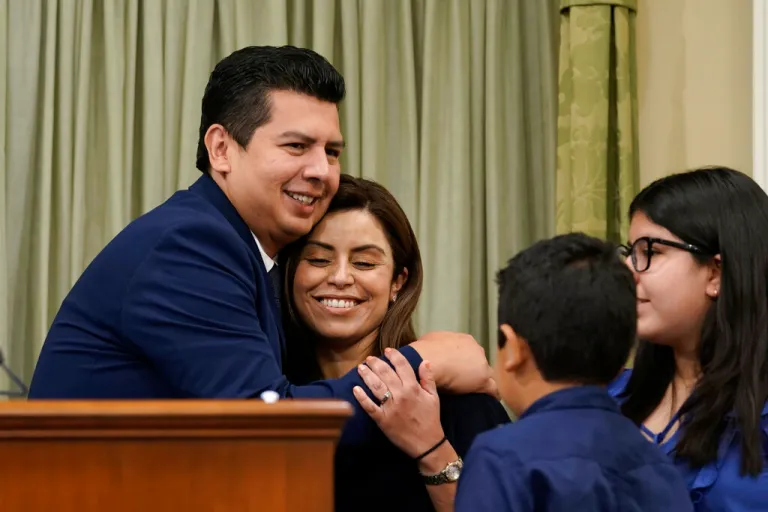 David Alvarez hugs his wife, Xochitl, after he was sworn into the California Assembly as their children, daughter, Izel, 12, right and son Javier, 8, second from right, look on in Sacramento, Calif., Wednesday, June 15, 2022. Alvarez, a Democrat, won a special election on June 7, 2022 for the 80th Assembly District that was vacated by Democrat Lorena Gonzalez in January.