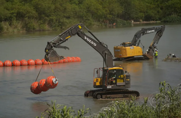 Workers continue to deploy large buoys to be used as a border barrier along the banks of the Rio Grande in Eagle Pass, Texas, Wednesday, July 12, 2023. The floating barrier is being deployed in an effort to block migrants from entering Texas from Mexico. (AP Photo/Eric Gay)