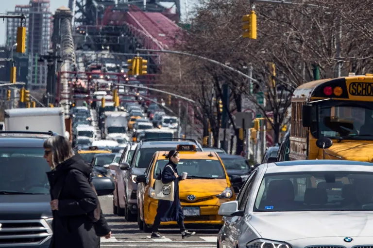 Pedestrians cross Delancey Street as congested traffic from Brooklyn enters Manhattan over the Williamsburg Bridge, March 28, 2019, in New York. The Metropolitan Transportation Authority, the state agency governing New York City transit, formally recognized the Governor's indefinite suspension of a revenue-generating vehicle toll, voting yes on a resolution to delay the implementation of $16.5 billion in subway and bus projects.