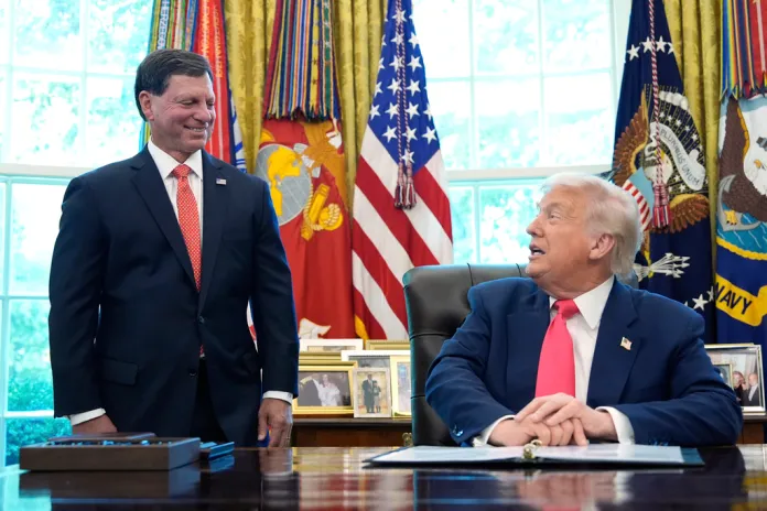 President Donald Trump speaks as Social Security Commissioner Frank Bisignano listens during an event in the Oval Office.