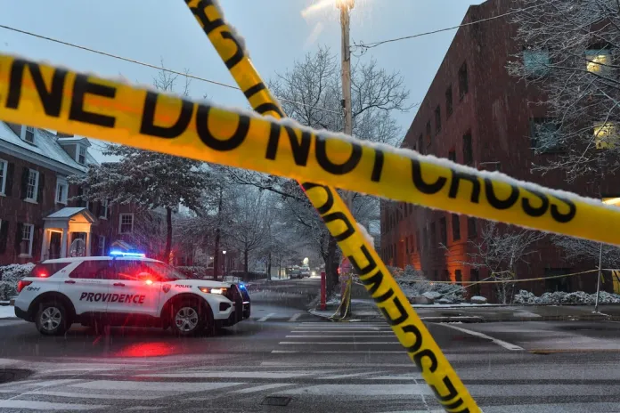 A police vehicle is parked at an intersection near crime scene tape at Brown University.