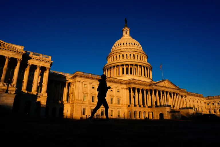 A runner jogs past the Capitol shortly after sunrise.