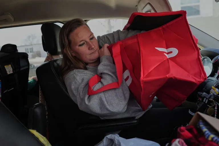 Dianna Tompkins checks on her new DoorDash bag in her car.