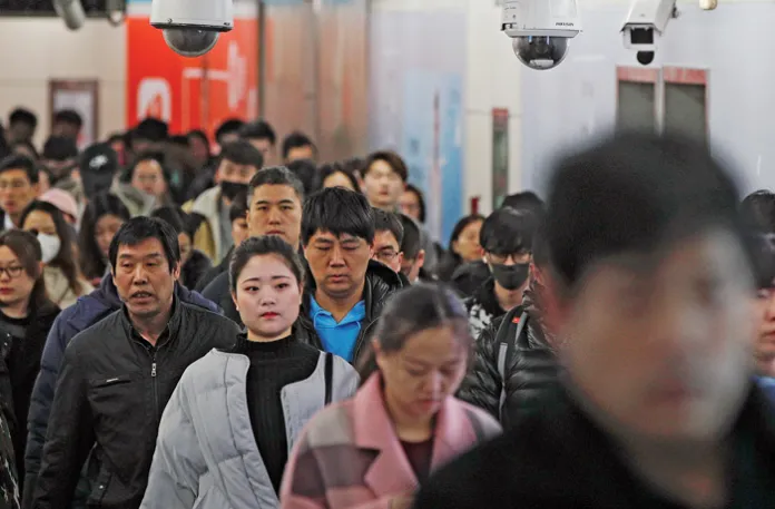 Commuters walk under a web of surveillance cameras in a subway station in Beijing, Feb. 26, 2019. The Chinese government uses facial and gait recognition to monitor people for its ‘social credit’ system. (Andy Wong/AP)