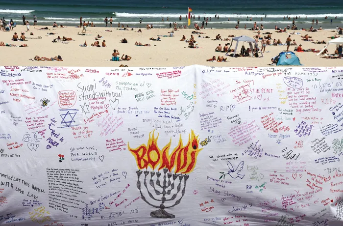 Beachgoers are seen behind a piece of cloth bearing messages from mourners to honor victims of the shooting that took place at the promenade of Bondi Beach in Sydney on Dec. 14. (Photo by David Gray/AFP via Getty Images)