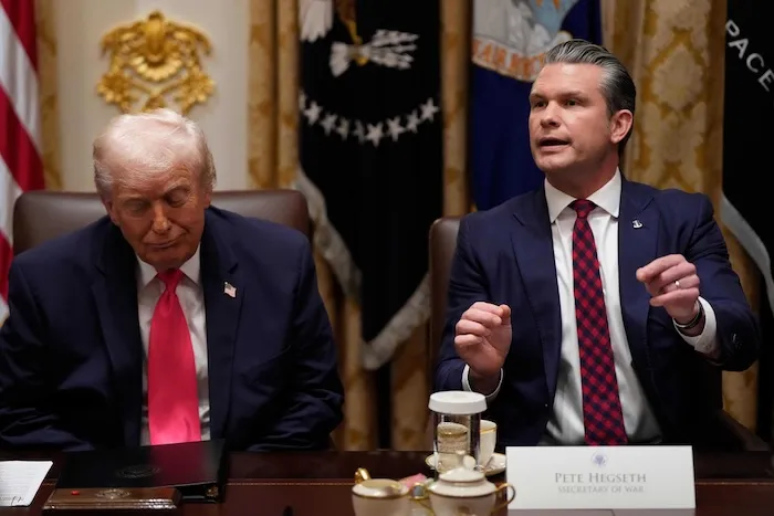 Secretary of War Pete Hegseth speaks as President Donald Trump listens during a Cabinet meeting at the White House.