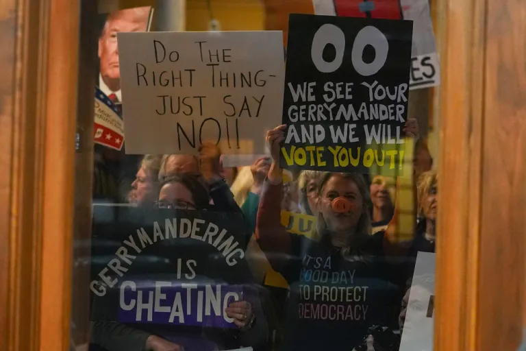 Protesters are seen through a window in the Senate Chamber during dissuasion before a vote to redistrict the state's congressional map.