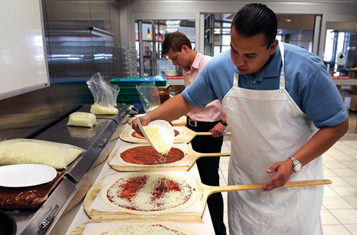 Product development specialists put tomato sauce and mozzerella cheese on pizzas in the Leprino Foods test kitchen. (Helen H. Richardson/The Denver Post via Getty Images)
