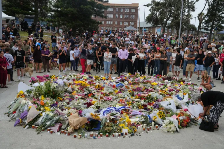 People gather around a tribute for shooting victims outside the Bondi Pavilion at Sydney's Bondi Beach.