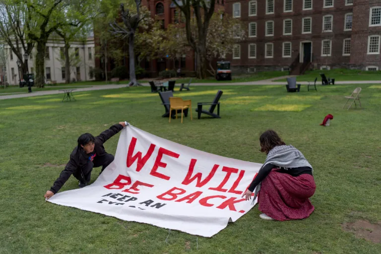 Demonstrators unfurl a banner on a lawn after an encampment protesting the Israel-Hamas war was taken down at Brown University.